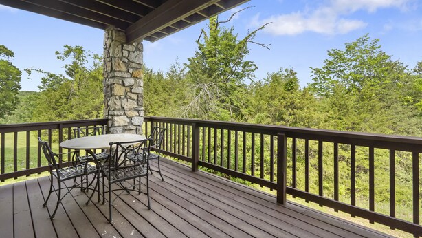 A wooden deck with a stone pillar, a round table, and four chairs. - Stonebridge Village Resort (Branson West)