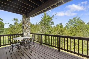 A wooden deck with a stone pillar, a round table, and four chairs. - Stonebridge Village Resort (Branson West)