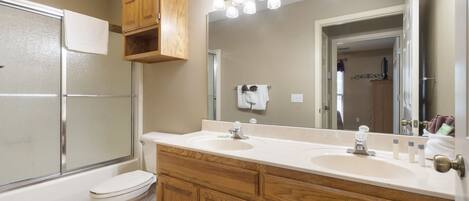 A bathroom with a double sink vanity, a mirror, and a shower enclosure.