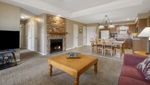 A spacious living room with a fireplace, a dining area, and a kitchen. - Stonebridge Village Resort (Branson West)