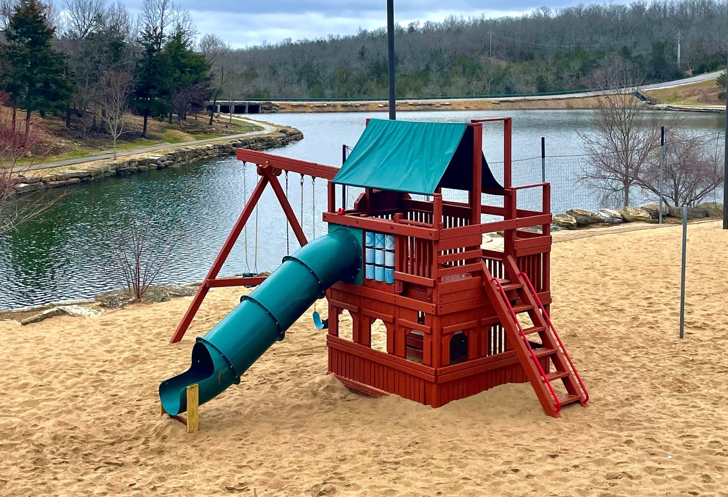 Eine Spielkonstruktion am Strand mit Rutsche, umgeben von Sand und einem See.