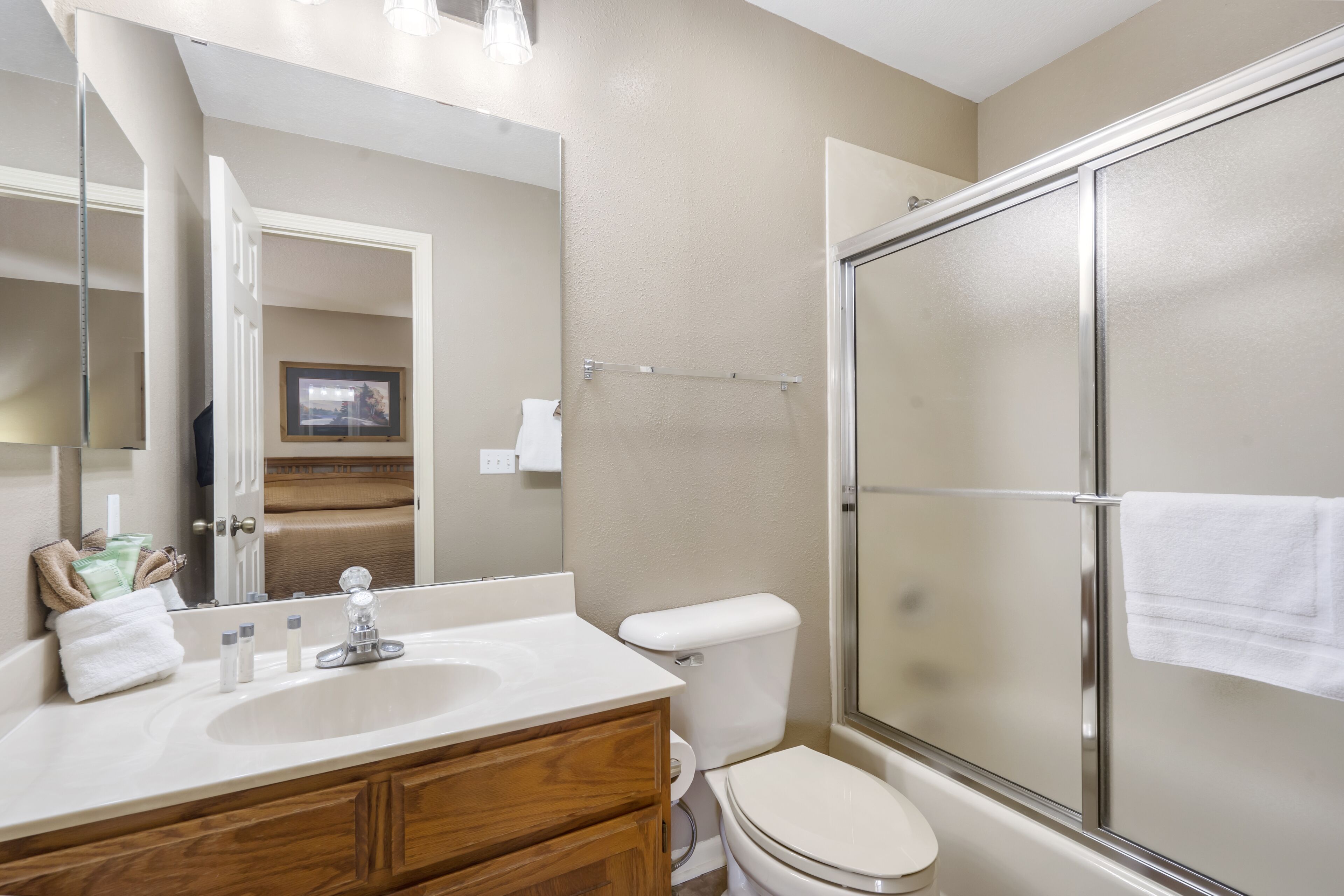 Une salle de bain équipée d’un lavabo, d’un miroir, de toilettes et d’une douche à parois en verre.