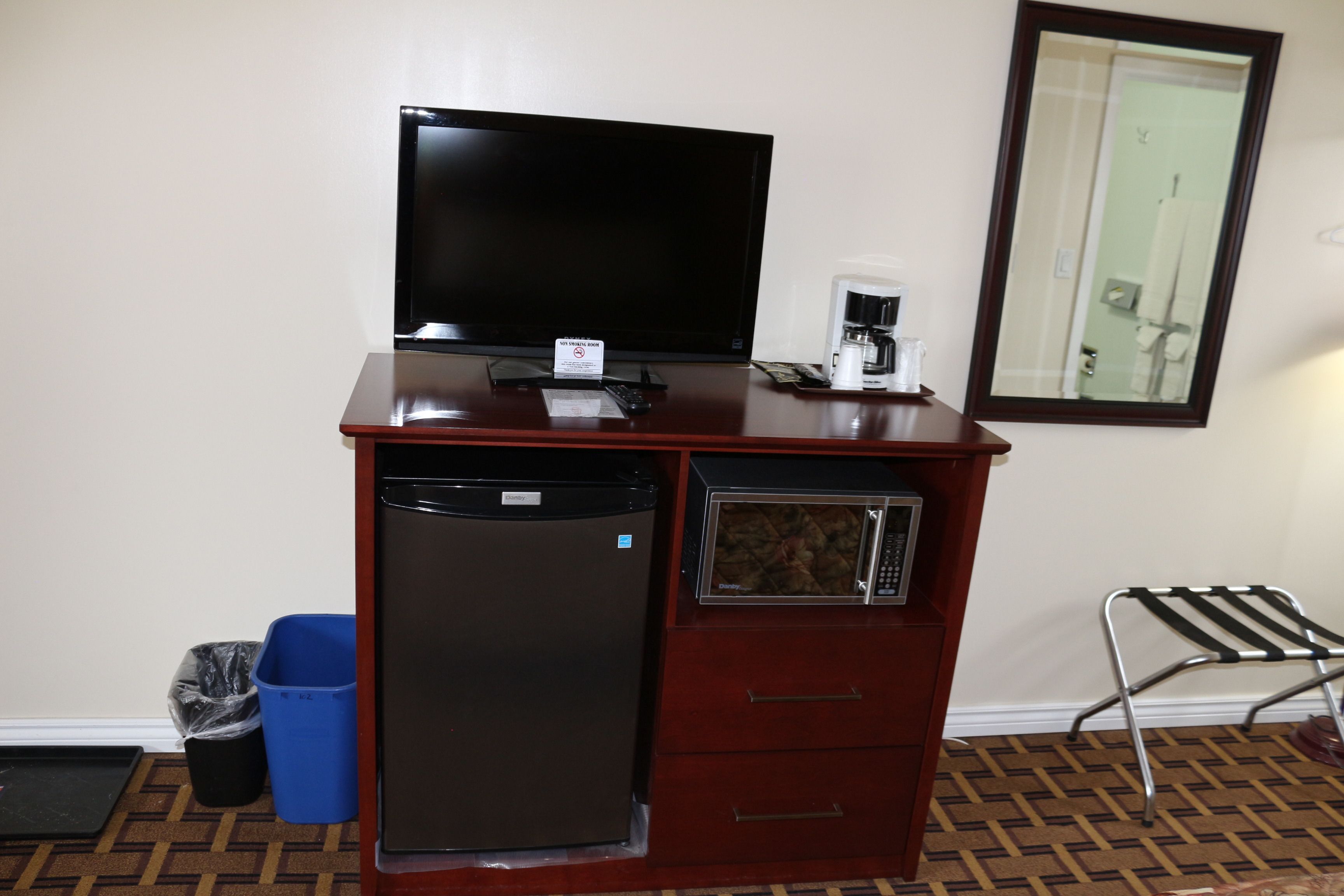 Una kitchenette compacta con refrigerador, microondas, cafetera y televisor de pantalla plana.