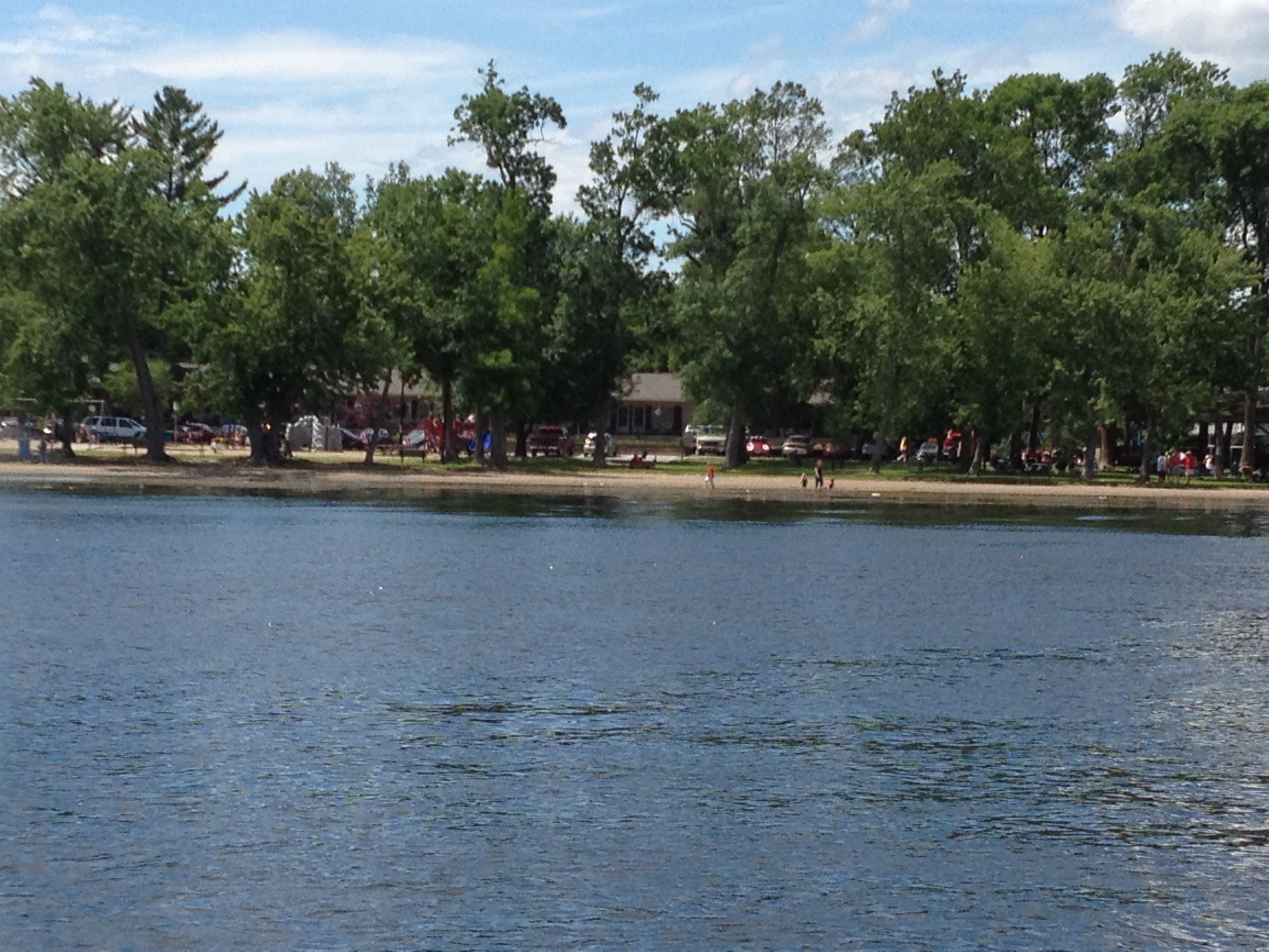 A lakeside view with trees and a building in the background.