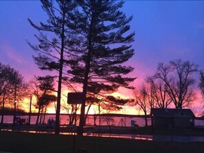 A sunset over a body of water with trees and a house in the foreground. - Park Place Motel & Suites (Tweed)