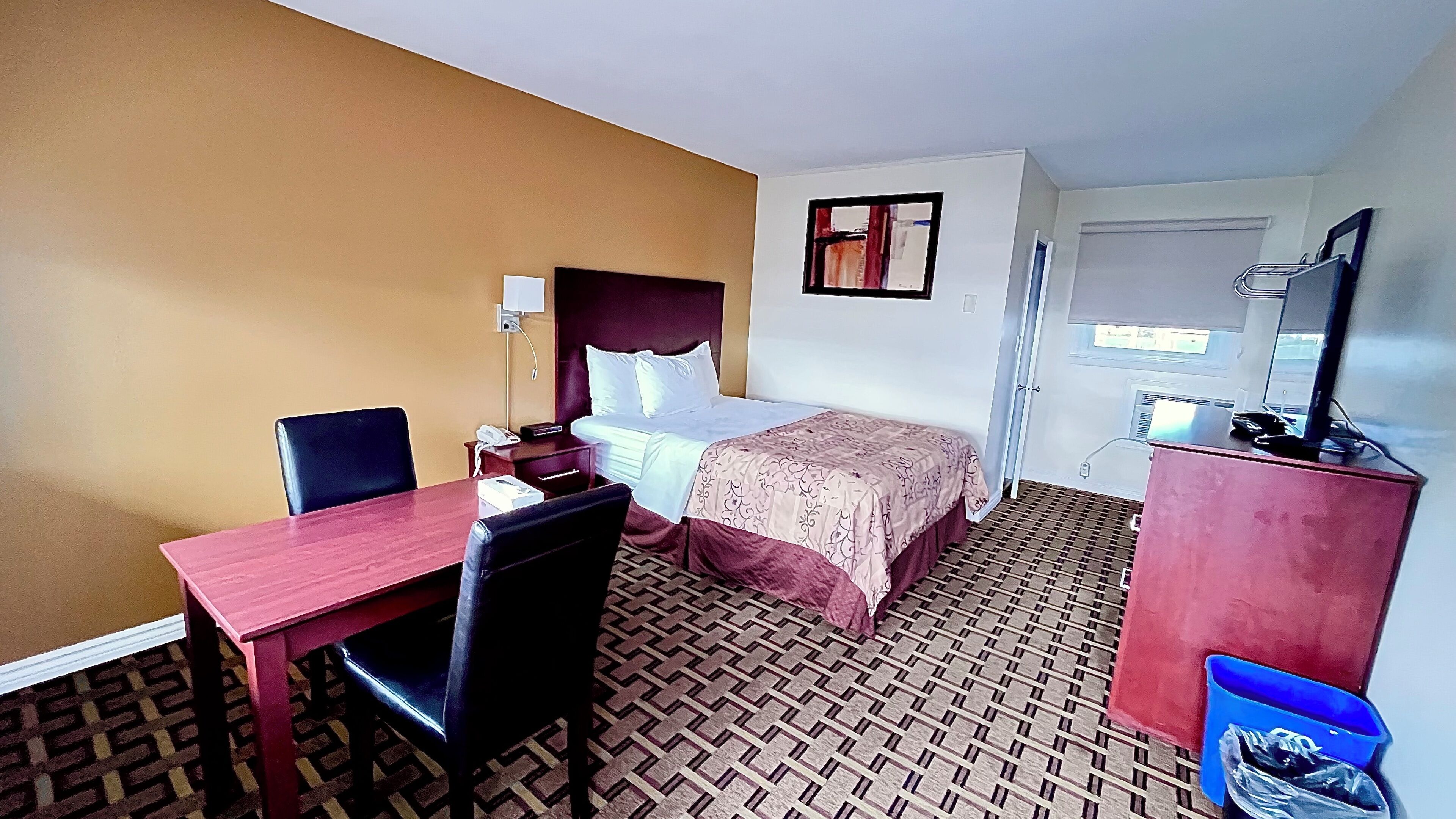 Una habitación de hotel con cama, escritorio, silla, cómoda y espejo.