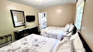 A hotel room with two beds, a desk, a chair, a mirror, and a window. - Park Place Motel & Suites (Tweed)