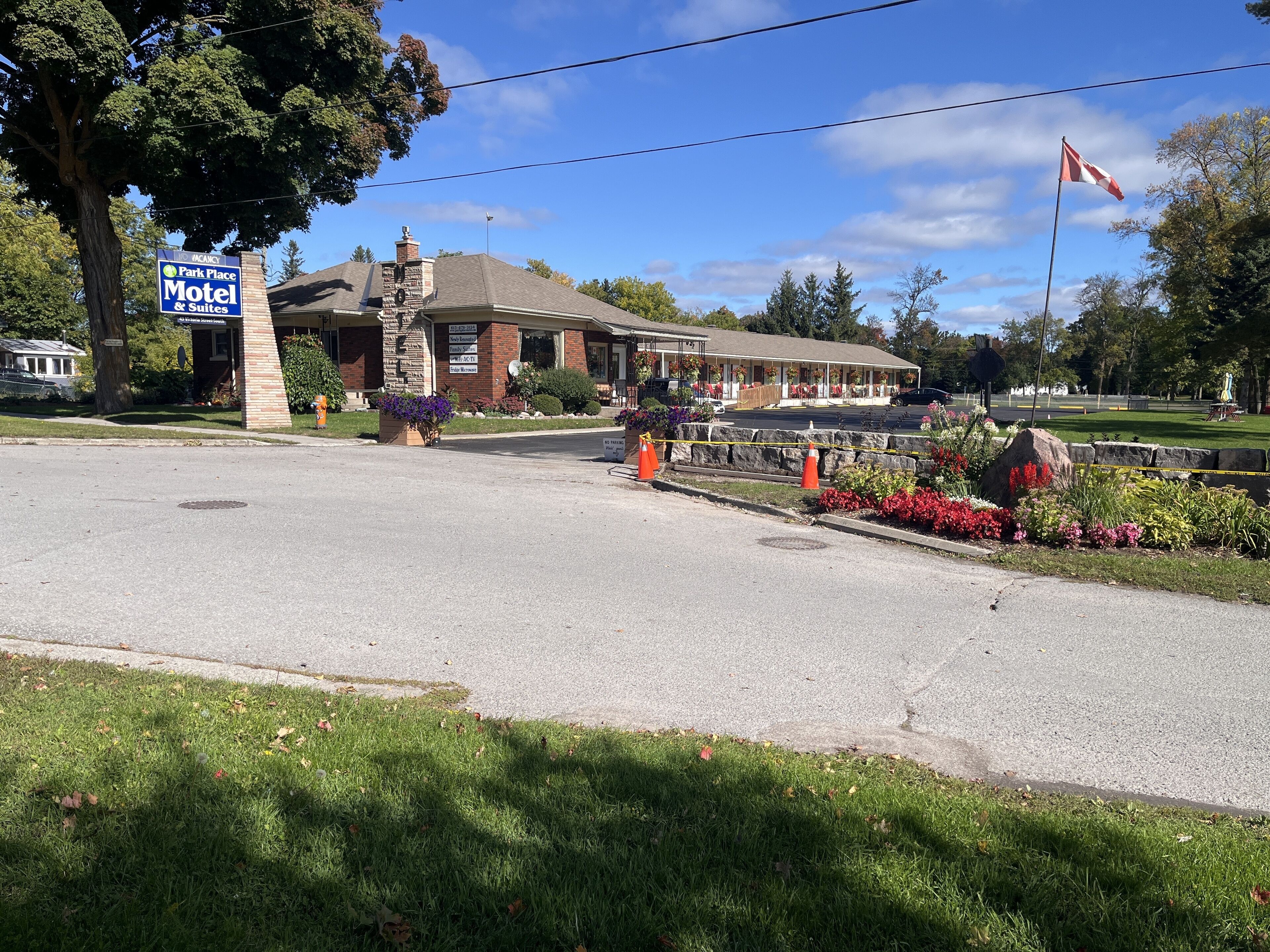 A motel with a brick facade, a large signboard, and a parking lot with orange traffic cones.
