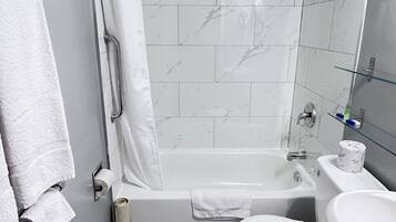 A modern bathroom with a bathtub, toilet, and sink.