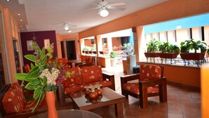 A hotel lobby with a seating area, a water dispenser, and a large window with plants. - Hotel La Rienda Misión Tequillan (Tequila)
