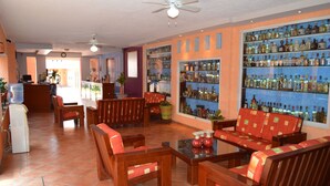 A lobby with wooden furniture, a water dispenser, and a bar area with shelves of bottles. - Hotel La Rienda Misión Tequillan (Tequila)