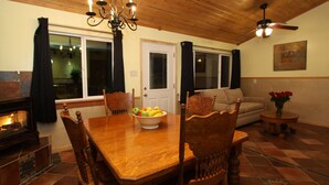 Un coin repas avec une table en bois, des chaises, un lustre et un ventilateur de plafond.