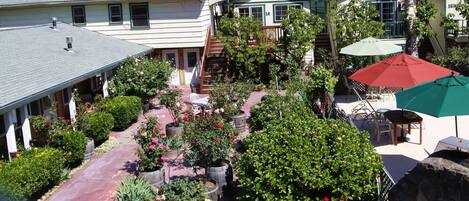 A courtyard with potted plants, outdoor seating, and a staircase leading to a second floor.