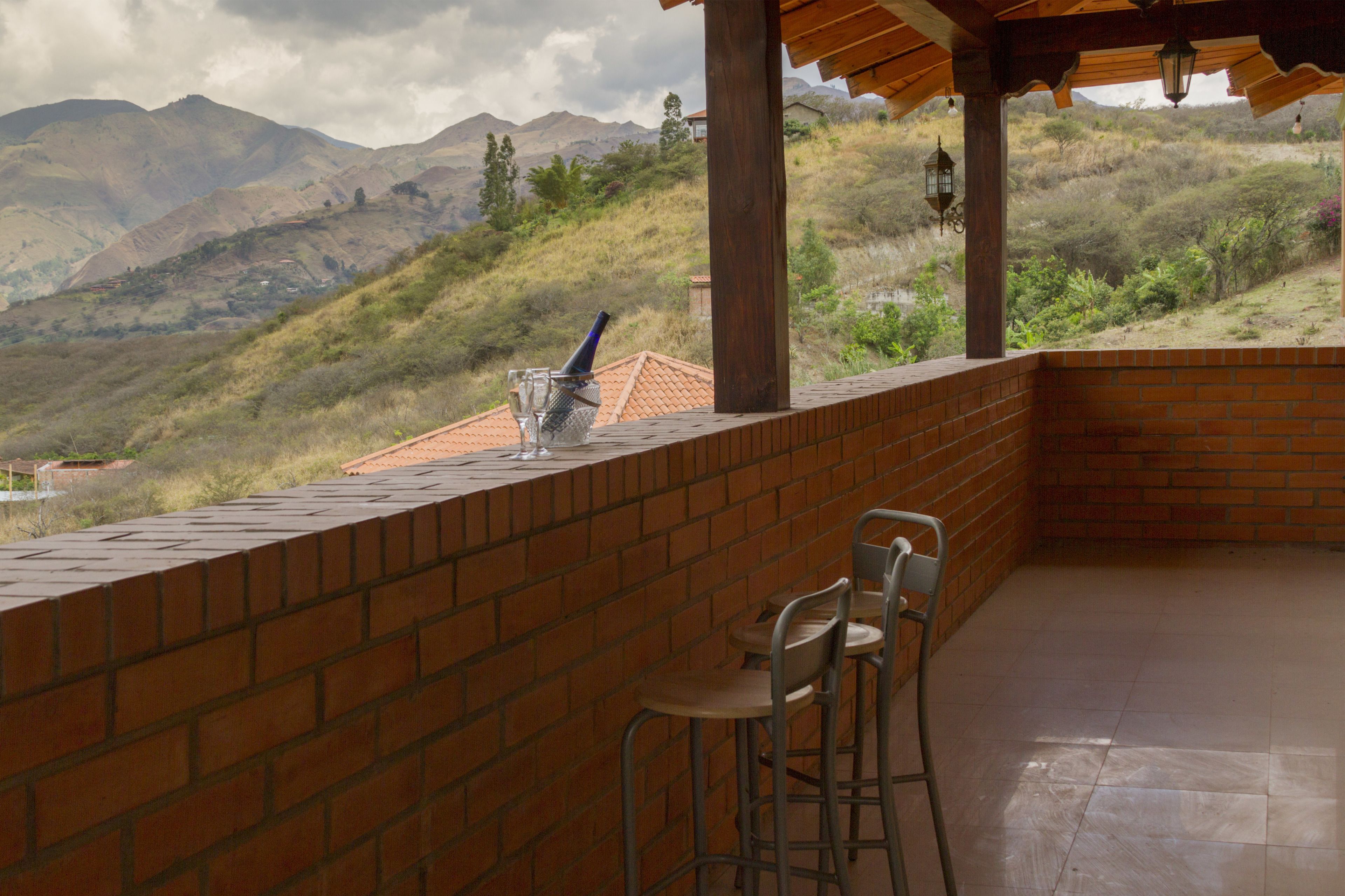 Una terraza con pared de ladrillo, dos sillas de metal y una mesa.