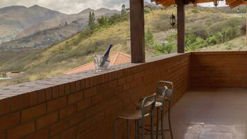 Una terraza con pared de ladrillo, dos sillas de metal y una mesa.