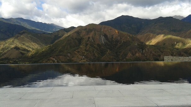 Un paysage de montagne avec une étendue d’eau qui reflète l’environnement et une structure en pierre.