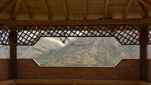 Un espace extérieur abrité, aménagé avec des sièges, et offrant une vue sur un paysage montagneux.