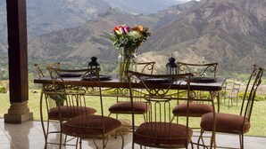 Une table à manger avec des chaises et un vase de fleurs, le tout placé devant un paysage montagneux.
