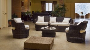 Un salon comprenant un canapé, deux fauteuils, une table basse et une cheminée.