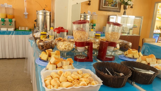 A buffet table with various food items and containers. - Hotel Guanabara (Belo Horizonte)