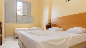 A hotel room with a large bed, a bedside table, a wardrobe, and a window with shutters. - Hotel Guanabara (Belo Horizonte)