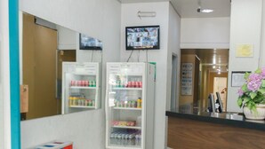 A reception area with two beverage dispensers, a television mounted on the wall, and a potted plant. - Hotel Guanabara (Belo Horizonte)