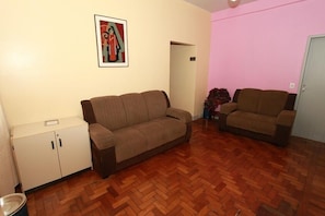A living room with a brown sofa, a white cabinet, and a pink wall. - Hotel Guanabara (Belo Horizonte)
