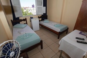A small room with two single beds, a small table, and a window with shutters. - Hotel Guanabara (Belo Horizonte)