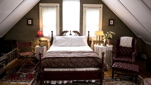 Un dormitorio con una cama grande, dos mesitas de noche, una silla y una ventana con cortinas.