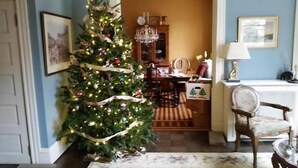Una sala de estar con un árbol de Navidad, una mesa de comedor, sillas y una araña.