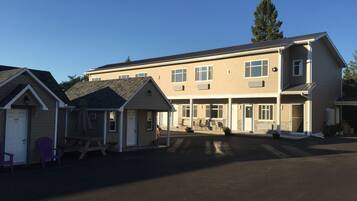 A two-story building with a covered patio area and a small adjacent structure.