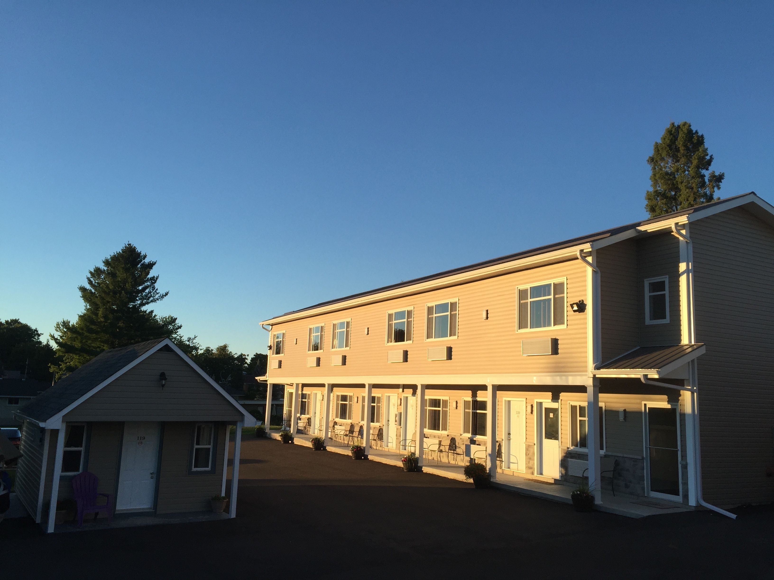 A two-story motel with a covered outdoor seating area and a small adjacent building.