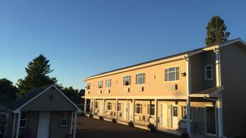A two-story motel with a covered outdoor seating area and a small adjacent building.