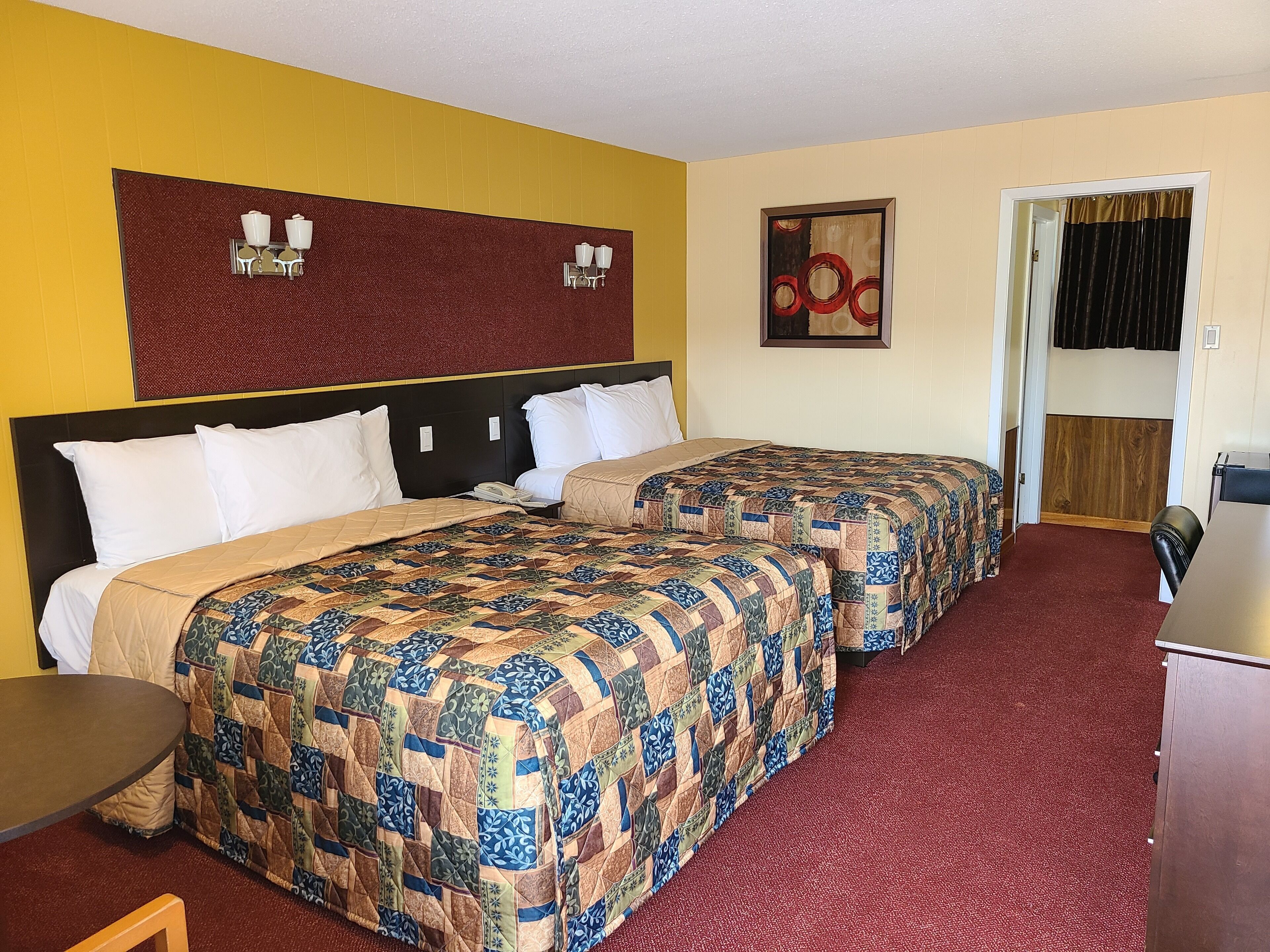 Habitación de hotel con dos camas, un escritorio, un teléfono y una puerta que da a un baño.