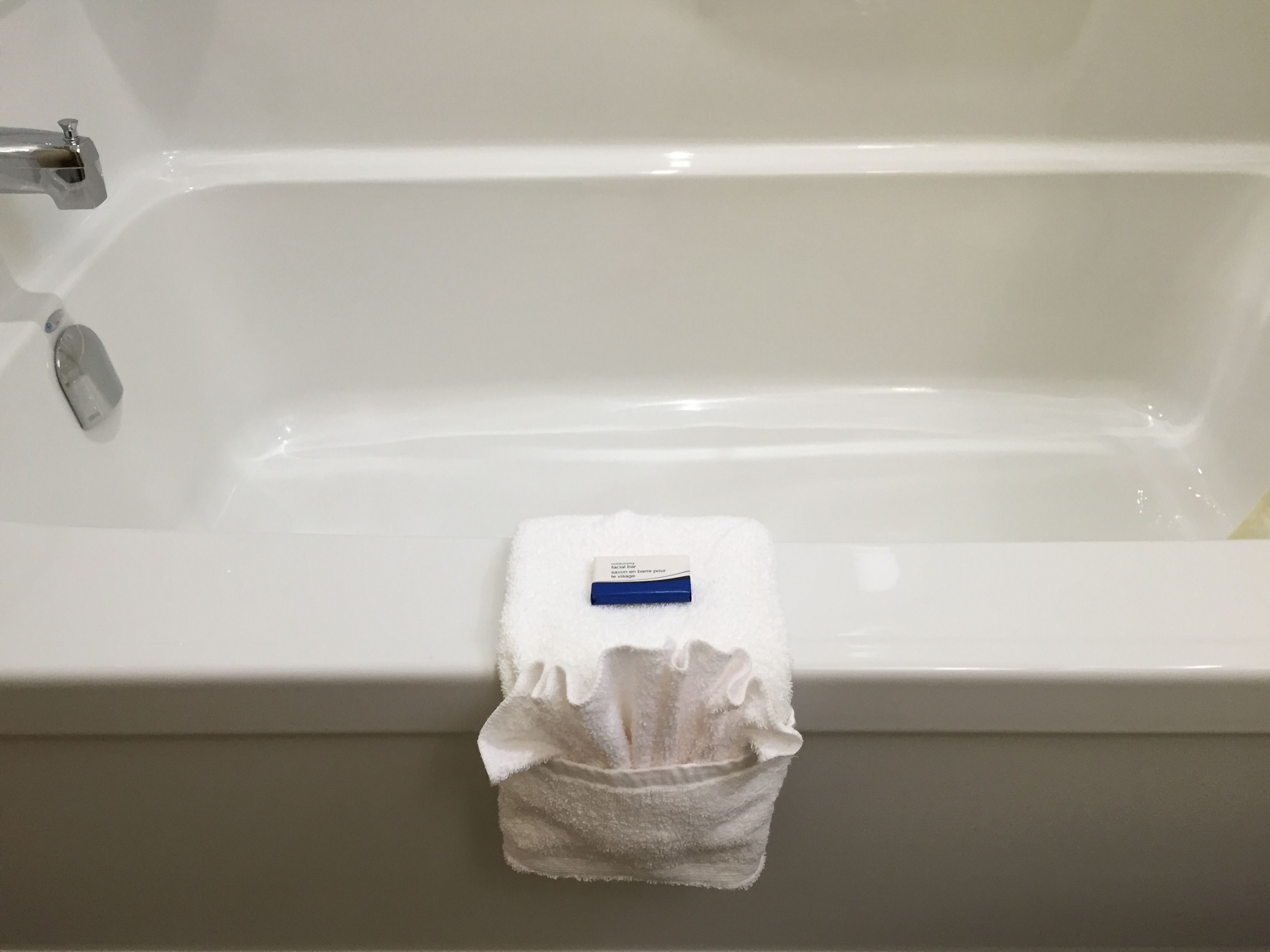 A white bathtub with a white towel hanging on the side.