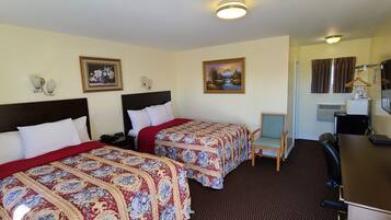 A hotel room with two beds, a desk, a chair, a TV, and a painting on the wall.