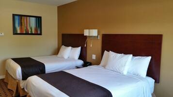Dos camas con cabeceras marrones y ropa de cama blanca en una habitación de hotel.