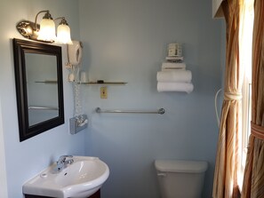 A bathroom with a sink, mirror, towel rack, and toilet. - Fox Motor Inn (Greater Napanee)