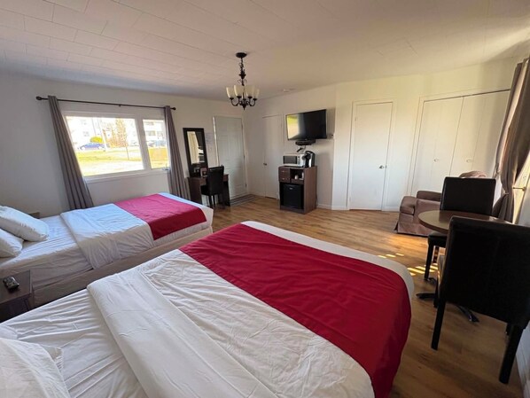 Hotelkamer met twee bedden, een bureau, een stoel, een televisie en uitzicht op het omliggende landschap.