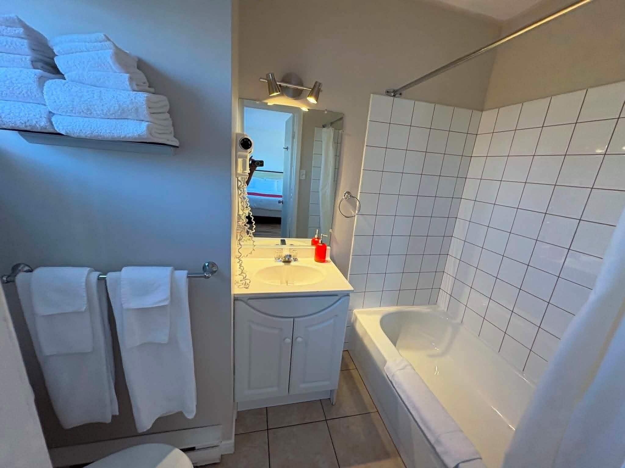 A bathroom with a bathtub, a sink, and a mirror.