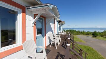 Guests can enjoy a porch with Adirondack chairs and a deck overlooking a body of water and distant mountains.