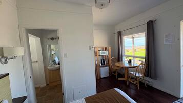 Ett hotellrum med en säng, ett skrivbord med en stol, ett fönster med utsikt och ett badrum med handfat och spegel.