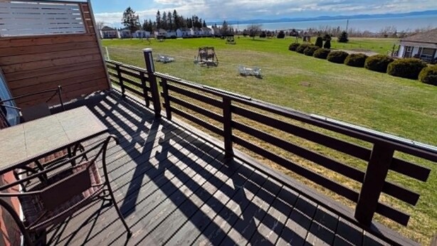 Um deck de madeira com vista para um campo gramado e montanhas ao longe.