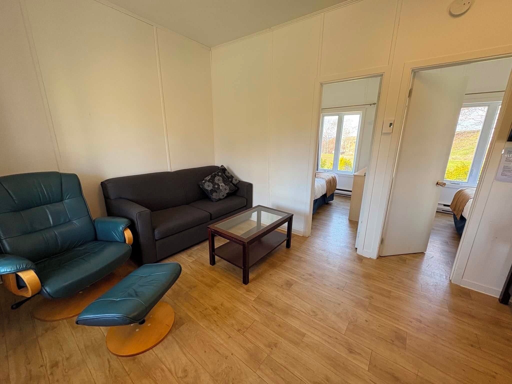 A living room with a sofa, a chair, a coffee table, and a wooden floor.