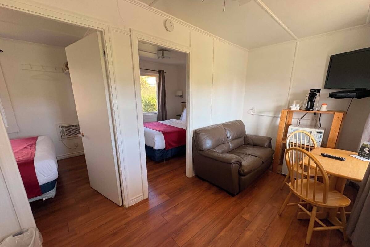 Una habitación con dos camas, un sofá, una mesa de madera con una silla y un televisor.