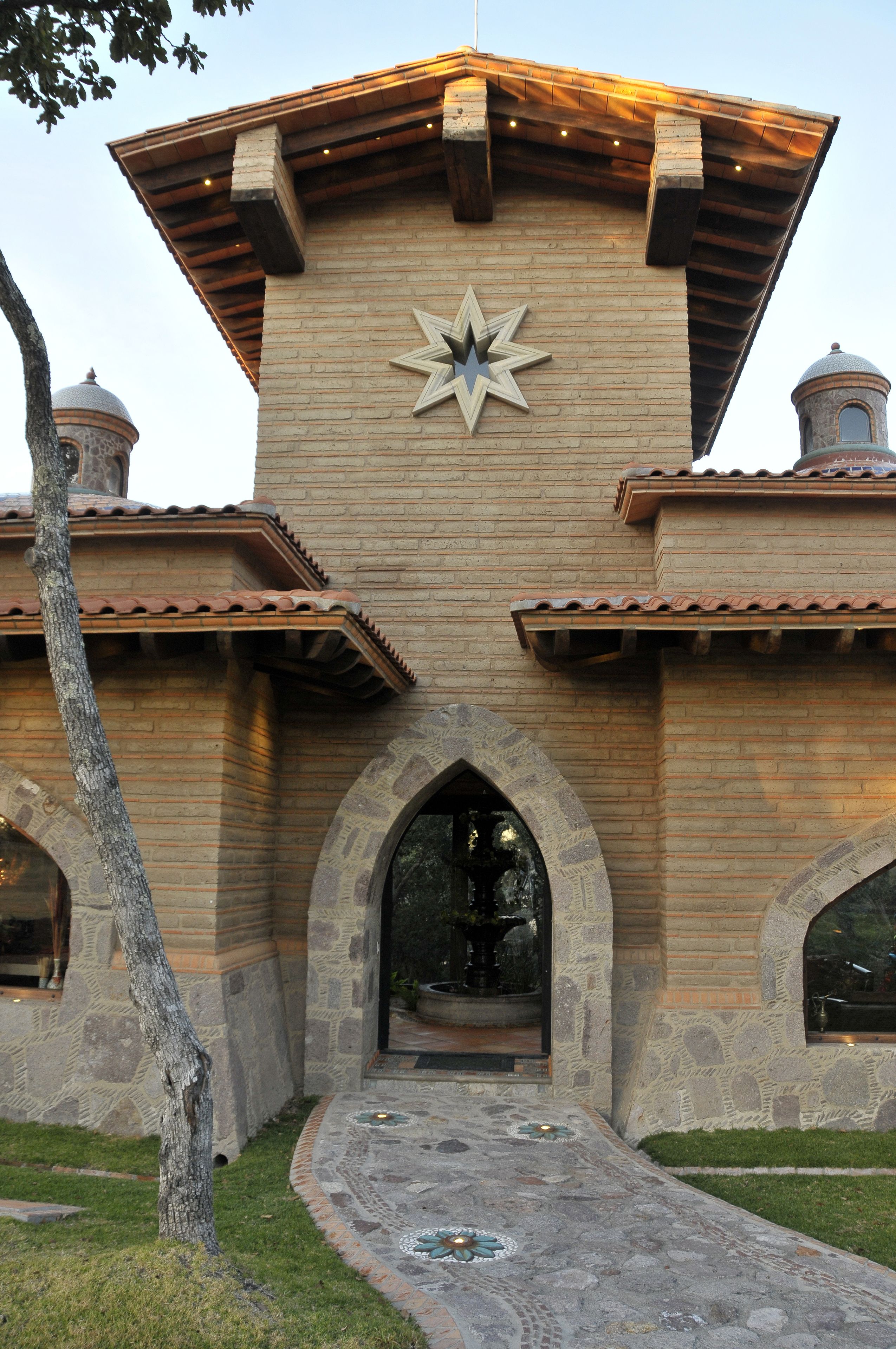 Un edificio con un emblema en forma de estrella, ventanas arqueadas y un camino de piedra que lleva a la entrada.