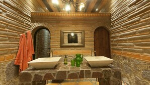 A stone-walled bathroom with two sinks, a mirror, and a chandelier. - Luxury Rancho la Loma (San Felipe)