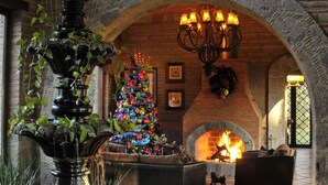 A fireplace with a stone arch, a Christmas tree, and a fountain in a lobby. - Luxury Rancho la Loma (San Felipe)