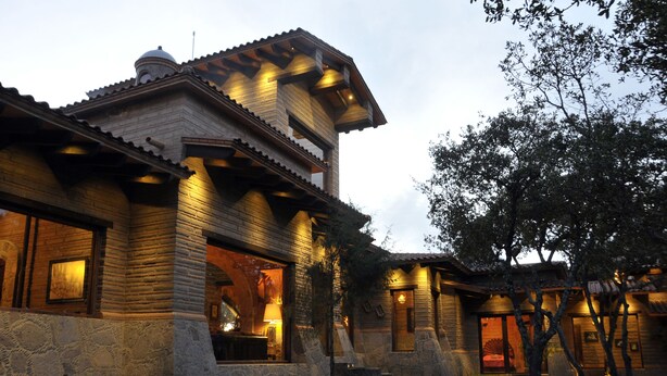 A rustic log cabin with a stone foundation, wooden beams, and a balcony. - Luxury Rancho la Loma (San Felipe)