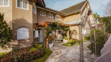 A house with a paved courtyard, a covered seating area, and a garden with flowers.